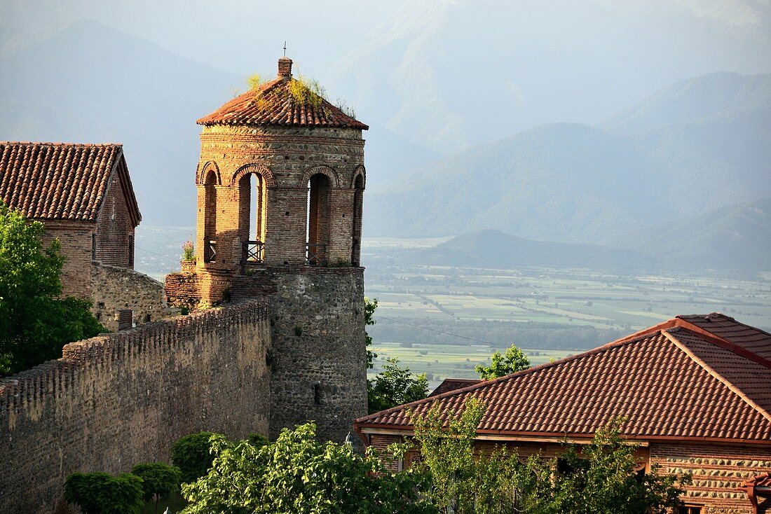 Medieval stone tower of the fortress of Telavi with green landscape and Caucasus mountains in the background, Kakheti, Eastern Georgia
