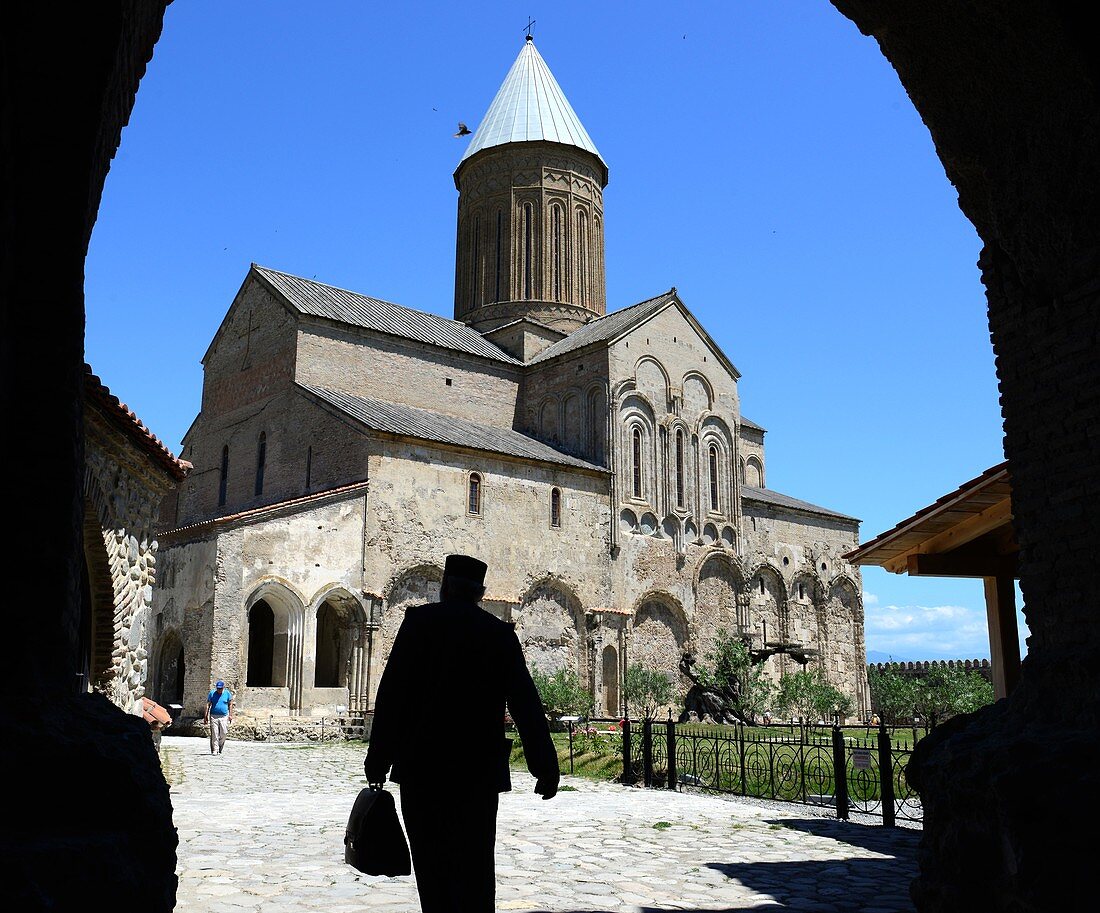 Mönch mit Aktentasche kommt in den Hof des Klosters Alaverdi, Kachetien, Georgien