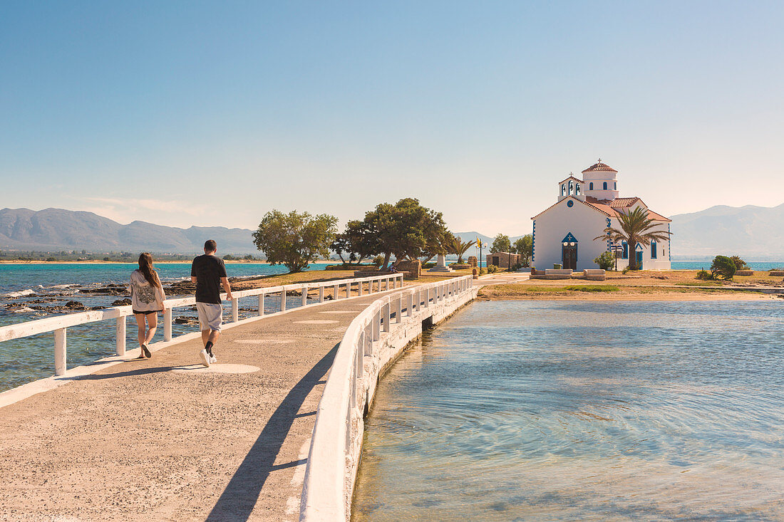 Tourists walking on the bridge that link Elafonissos island with the orthodox church of St. Spyridon, Elafonissos, Laconia region, Peloponnese, Greece, Europe