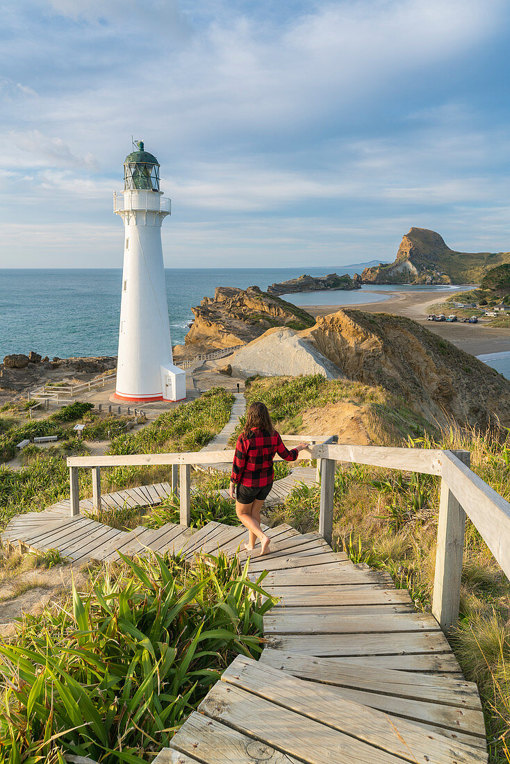 Woman descending the footpath towards Castlepoint lighthouse. Castlepoint, Wairarapa region, North Island, New Zealand.