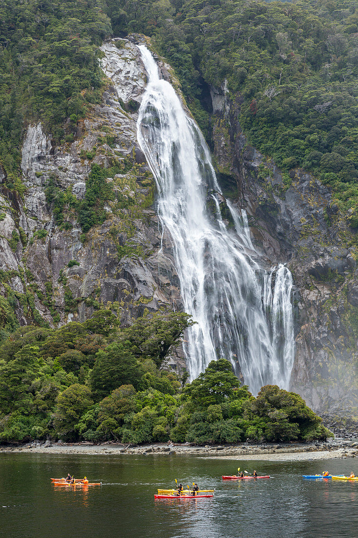 People kayaking around Bowen Falls in Milford Sound in summer. Fiordland NP, Southland district, Southland region, South Island, New Zealand.