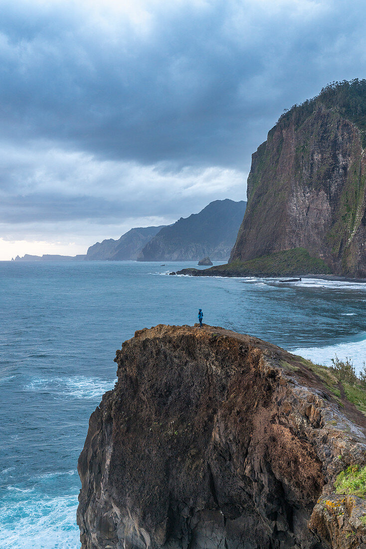 Person on a cliff watching the sunrise. Faial, Santana municipality, Madeira region, Portugal.
