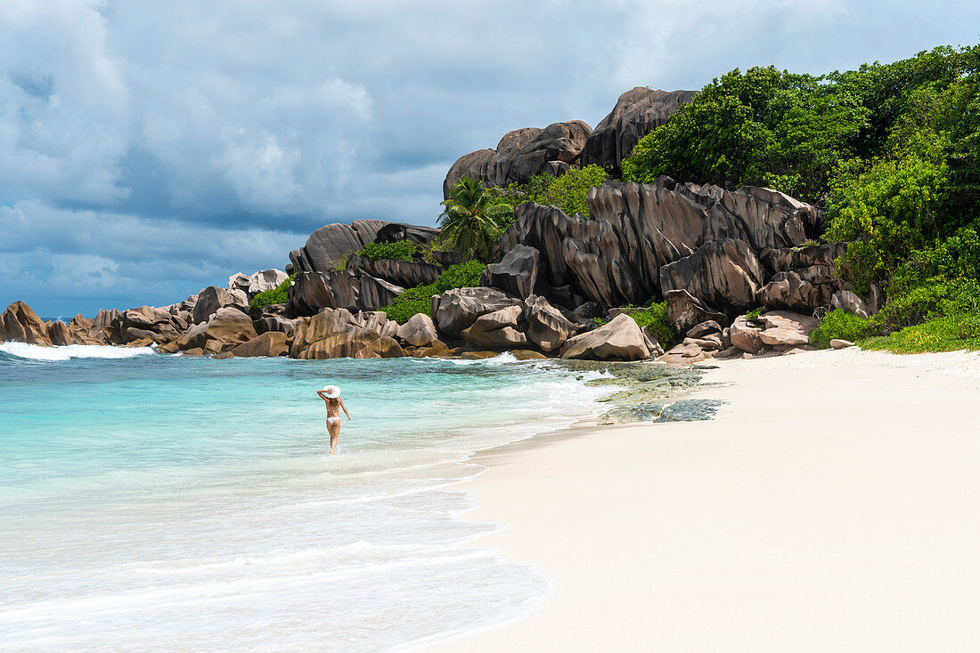 A young lady strolling along Grand Anse. La Digue island, Seychelles, Africa