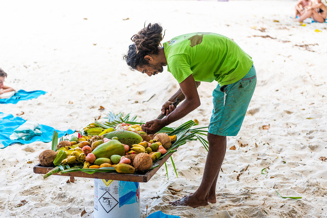 Local man preparing a plate of fresh tropical fruits. Praslin island, Seychelles, Africa