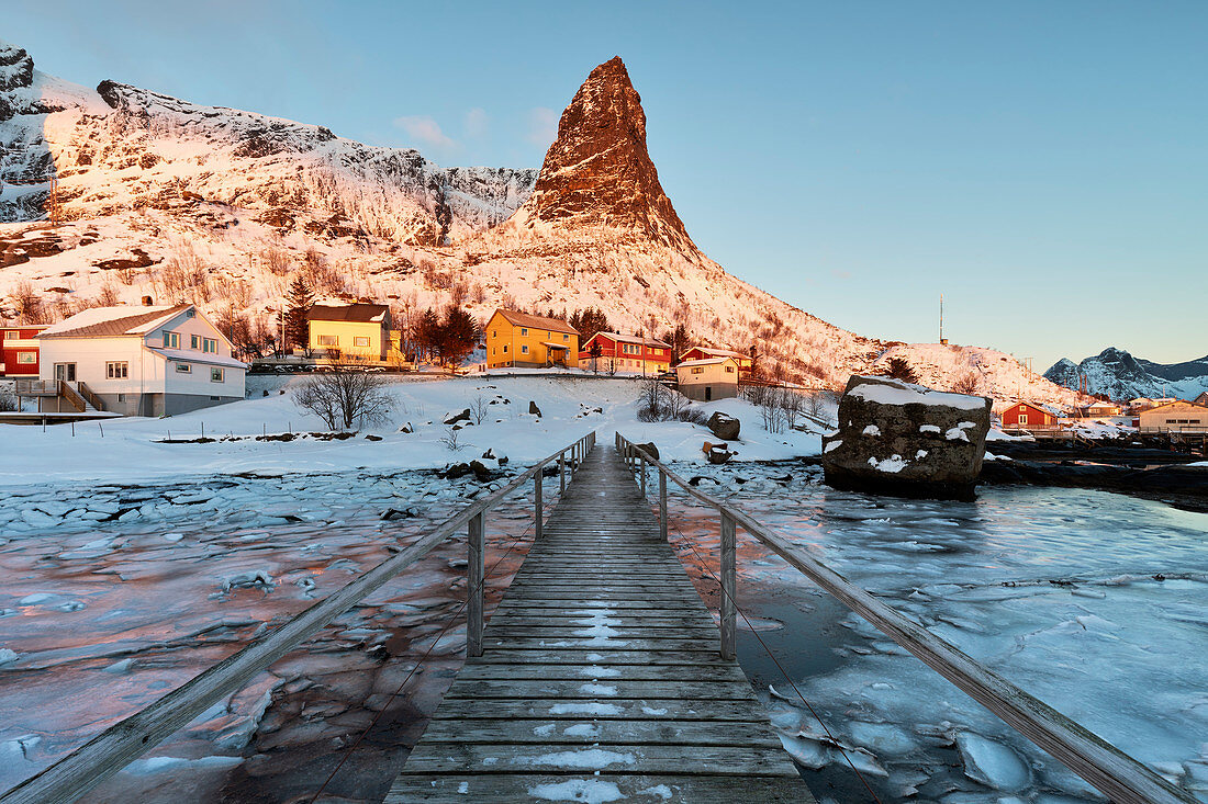 Der ikonenhafte Hammmarskaftet-Berg in Reine-Dorf bei Sonnenaufgang am Wintertag, Lofoten-Inseln, Nord-Norwegen, Europa