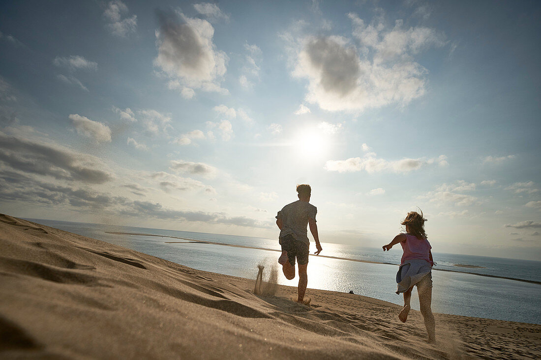 Junge und Mädchen rennen die Düne hinunter, Dune d'Arcachon, Französische Atlantikküste, Aquitanien, Frankreich