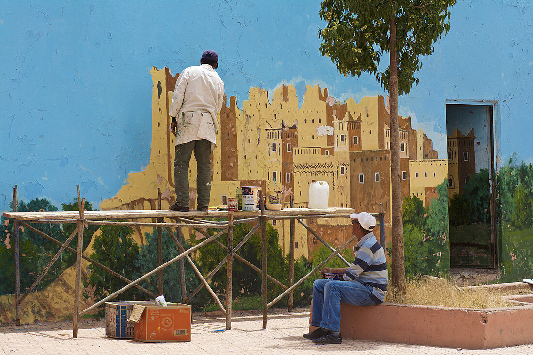 Men paint a wall in El Kelaâ M'Gouna with a kashbah, Dadestal High Atlas, Morocco