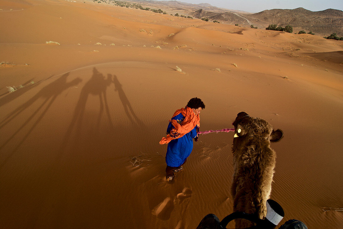 Kamel wird von Berber durch Dünen geführt, im Dünengebiet Erg Chebbi, Tafilalet, Marokko