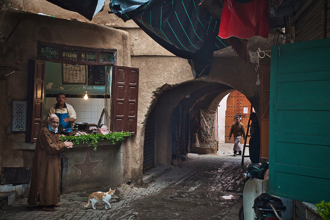 Fischhändler in der Altstadt von Marrakesch mit Torbogen und bärtigem Kunden, Marokko, Afrika