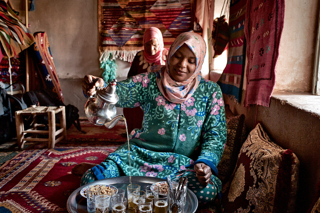 Berber Frau in einem maison traditionelle in Ait Benhaddou schenkt Pfefferminztee ein, Hoher Atlas, Marokko