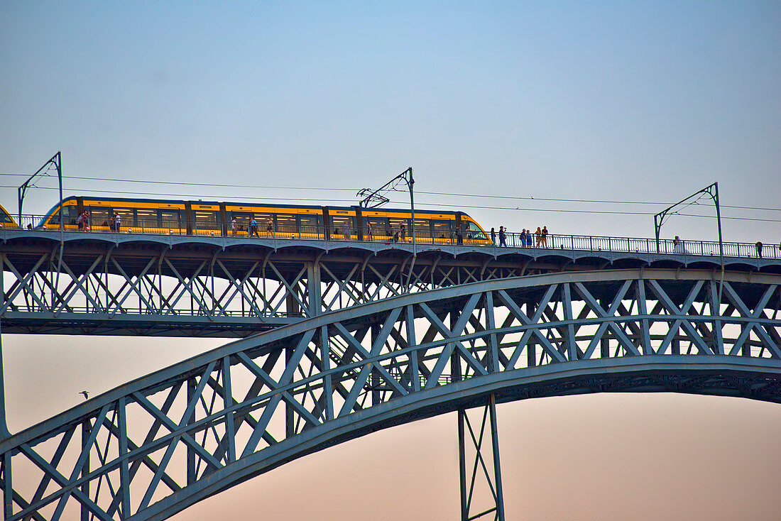 View to Ponte Dom Luis I with suburban train and pedestrians after sunset, Porto, Portugal