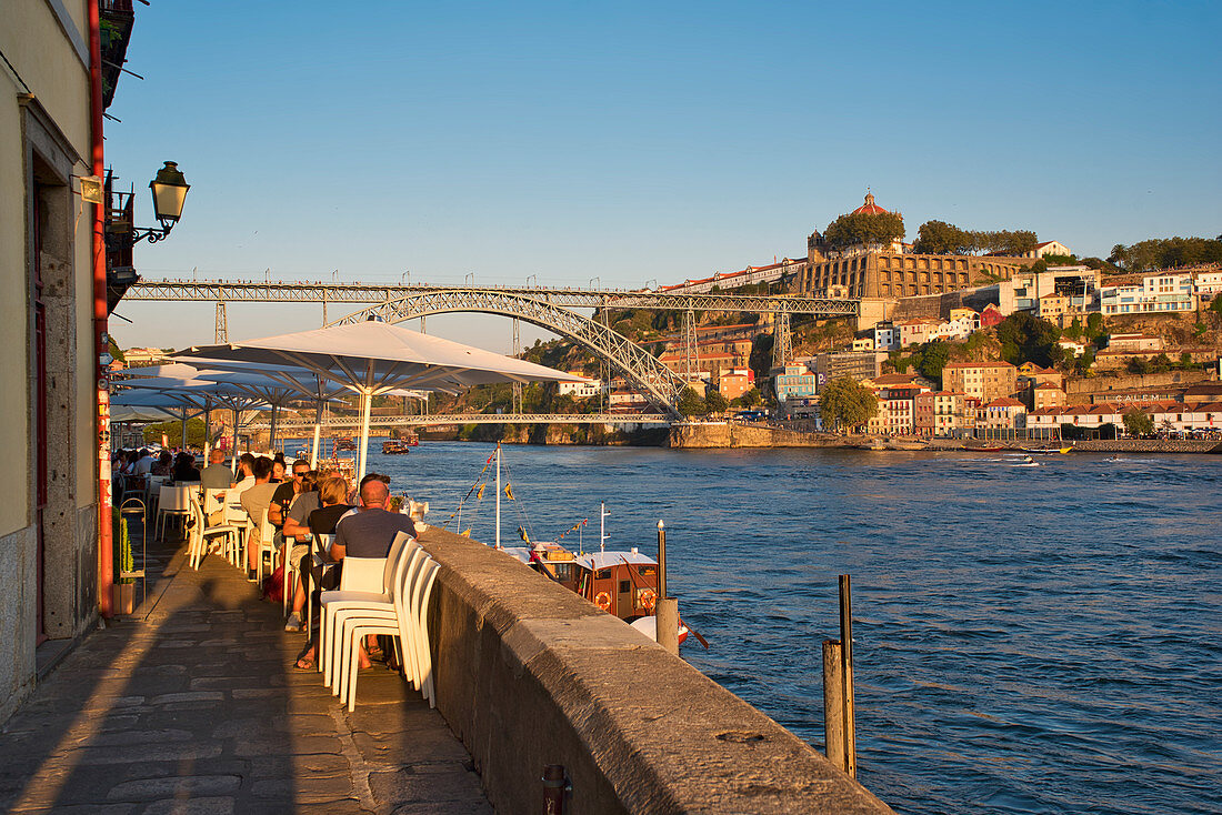 Restaurants on the Cais da Ribeira on the Douro with a view to Ponte Dom Luis I. Porto, Portugal