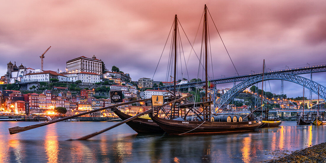 Rabelo boats with port wine barrels on the banks of the Douro at dusk, Porto, Portugal