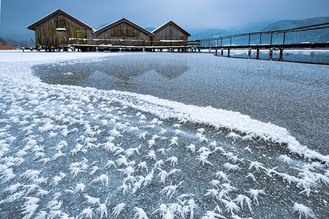 Ice flowers on the gefelteenen Kochelsee overlooking the three wooden huts and the jetty, in the background is fog, winter, Schlehdorf, Alpine foothills, Bavaria, Germany