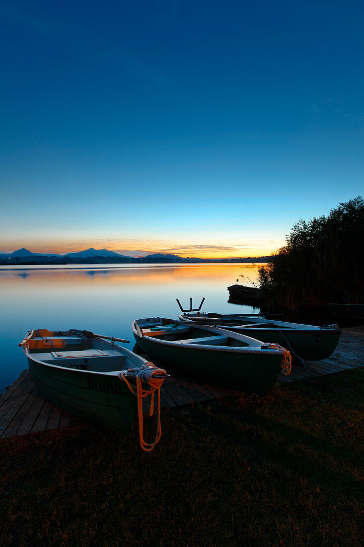 Rowing boats on the dock at Hopfensee at sunset, Bavaria, Germany