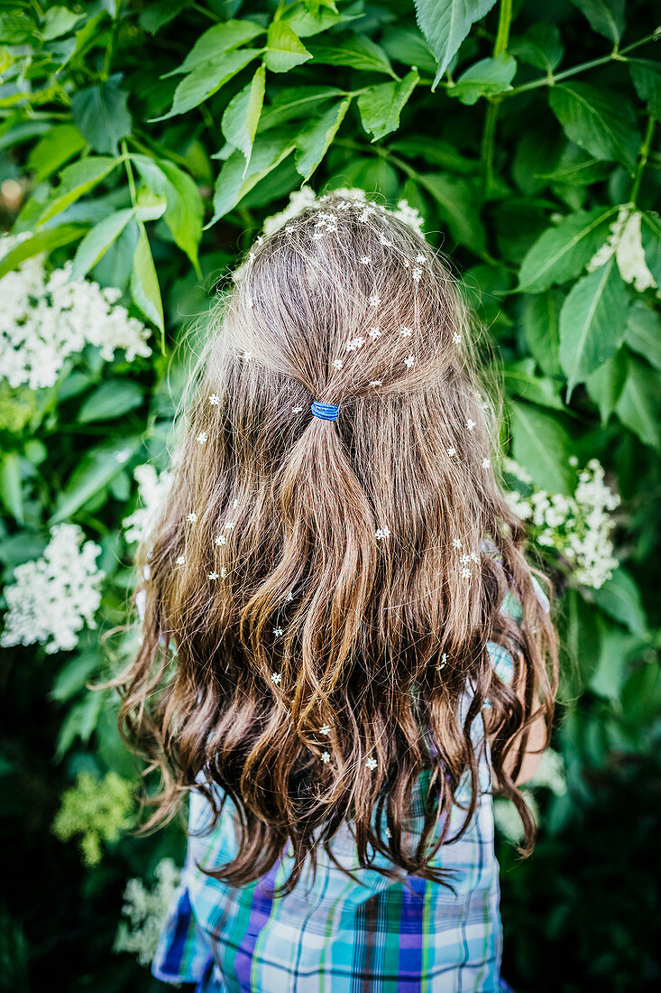 Girl with flowers in hair at blooming bush