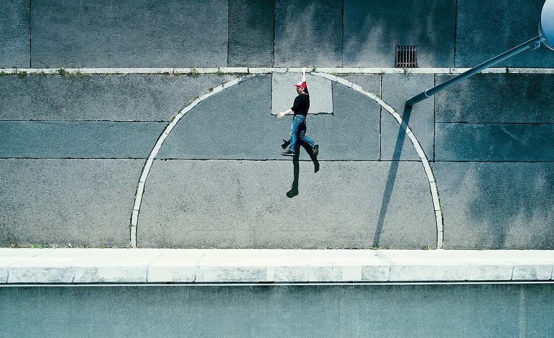 View from above young man hanging from urban curb