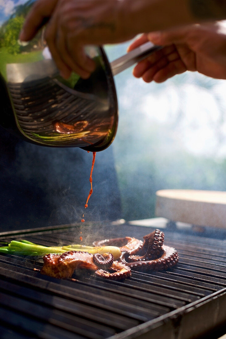 Chef pouring sauce over squid on octopus