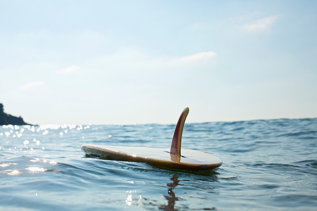 Surfboard floating on sunny blue ocean