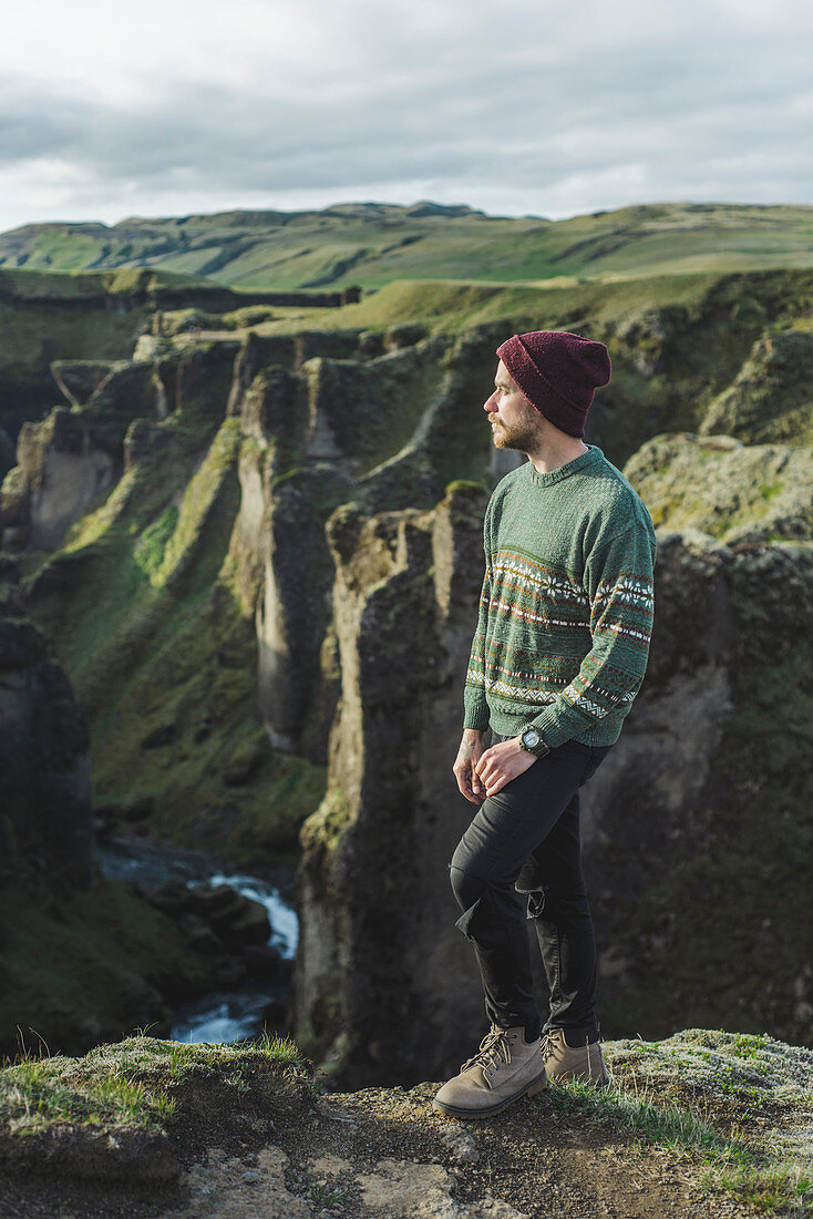 Junger Mann steht der auf Klippe über Schlucht in Kirkjubaejarklaustur, Island