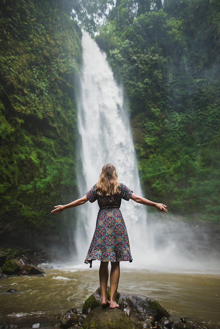 Frau steht am Wasserfall auf Bali, Indonesien
