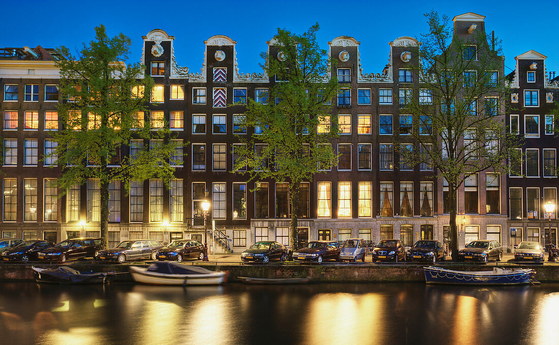 Autos und Häuser am Kanal bei Nacht, Amsterdam, Niederlande