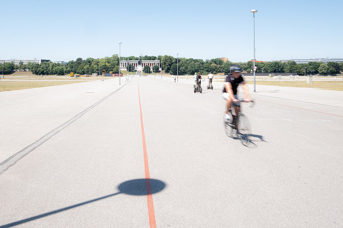Fahrradfahrer auf der Theresienwiese, im Hintergrund die Bavaria, München, Bayern, Deutschland