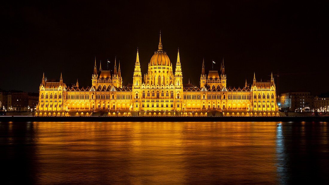 The lighted Budapest Parliament at night with the Danube in the foreground