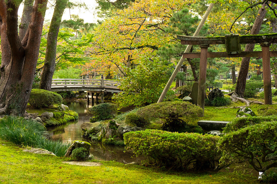 Hanambashi Brücke und ein Steintor umgeben von Herbstlaub im Kenrokuen Garden, Kanazawa, Ishigawa, Japan, Asien