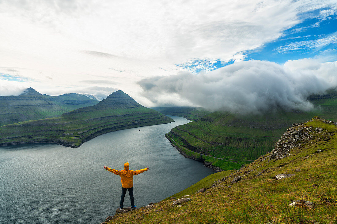 Man with open arms rejoices looking to the fjords, Funningur, Eysturoy island, Faroe Islands, Denmark, Europe