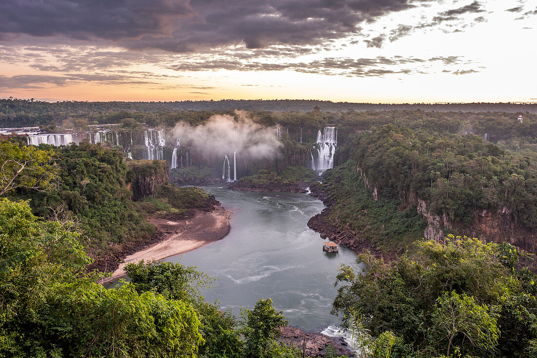 Scenic view of rainforest surrounding splashing Iguazu Falls at dusk, Parana, Brazil