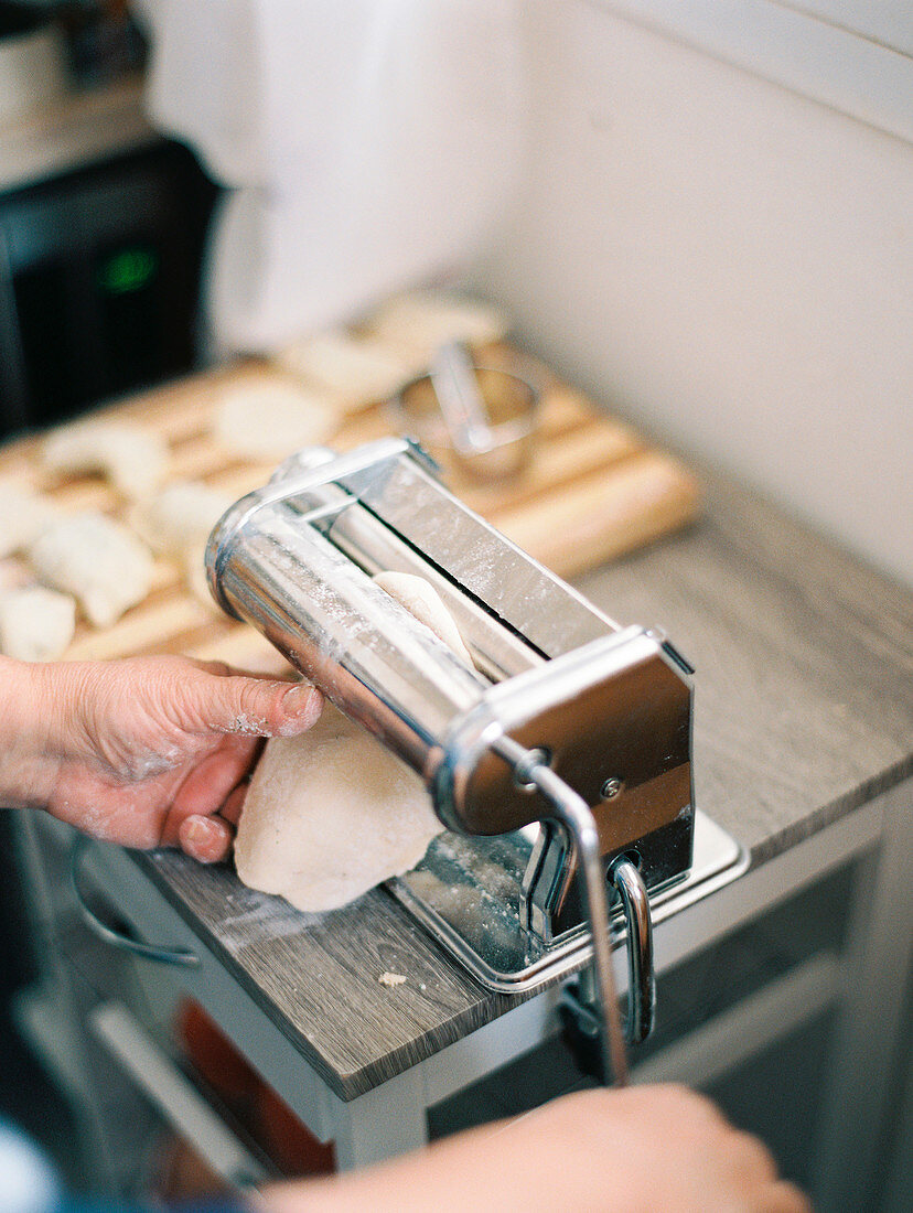 Close up of hands of woman making ravioli dumplings with machine