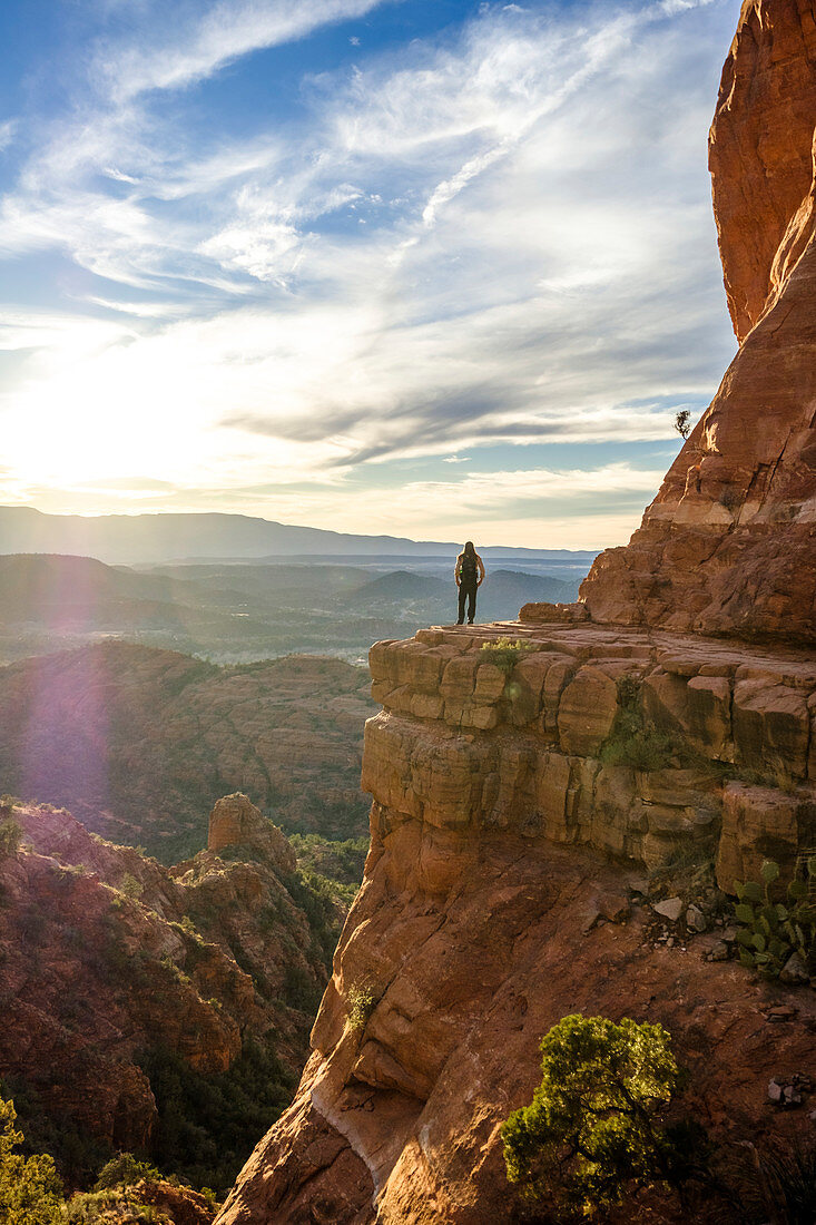 Distant view of female hiker standing at Cathedral Rock in Sedona, Arizona, USA