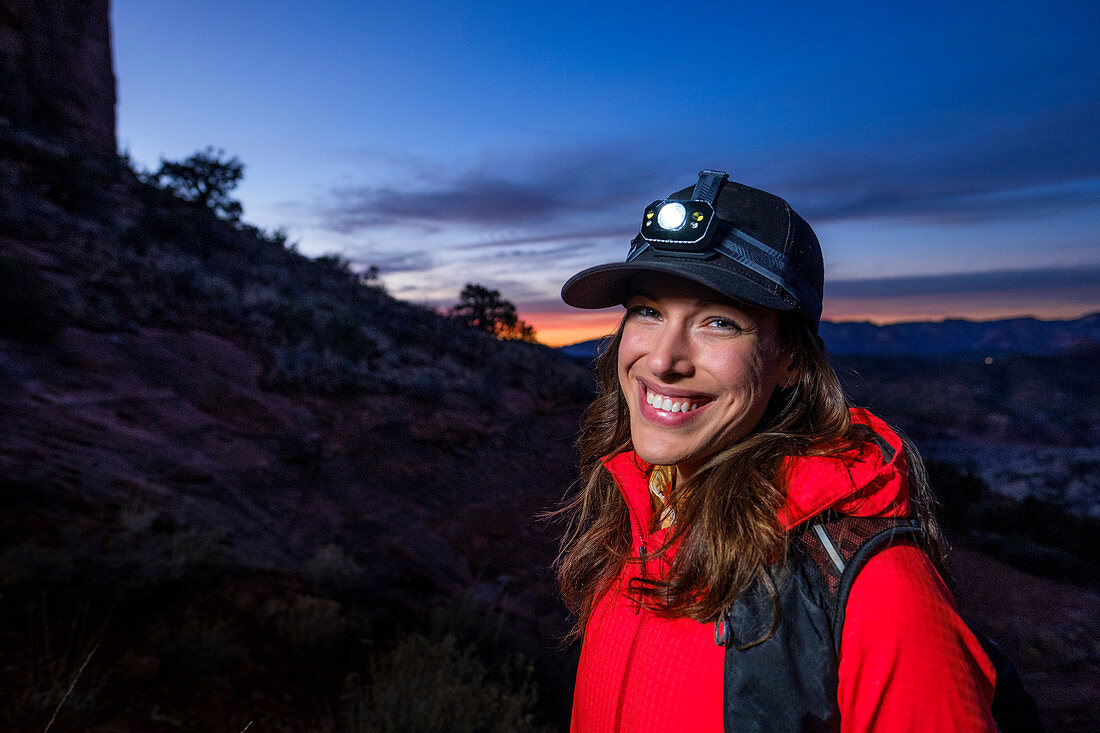Portrait of female hiker wearing headlamp standing at Cathedral Rock and smiling at camera, Arizona, USA