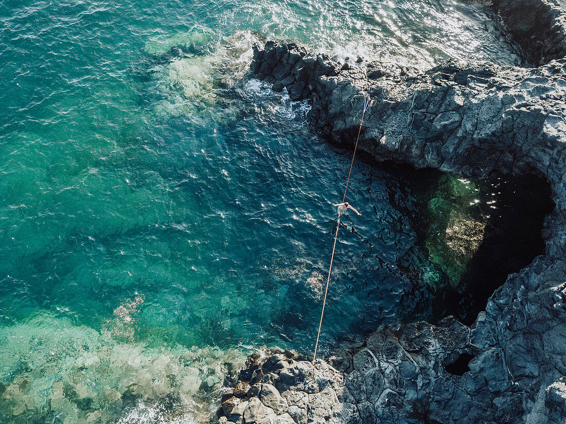 Blick auf Mann, der über Drahtseil im Meer balanciert, Teneriffa, Kanarische Inseln, Spanien