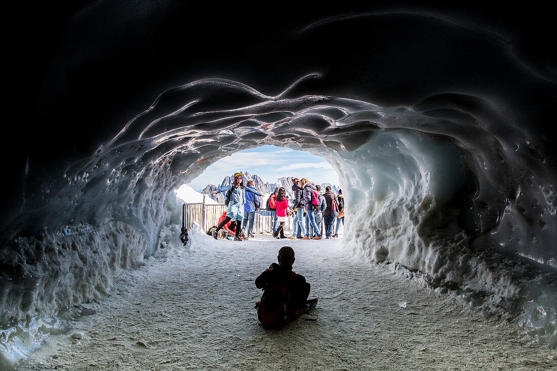 Tourists posing for photo in front of ice cave styled entrance, Chamonix Mont-Blanc, Haute Savoie, France