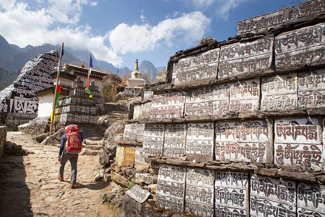 A trekker is walking past a big wall of Mani stones, with Buddhist prayer inscriptions. The trek to Everest Base Camp (EBC) is possibly the most dramatic and picturesque in the Nepalese Himalaya. Not only will you stand face to face with Mount Everest, Sagarmatha in Nepali language, at 8,848 m (29,029 ft), but you will be following in the footsteps of great mountaineers like Edmund Hillary and Tenzing Norgay. The trek is scenic and offers ever-changing Himalayan scenery through forests, hills and quaint villages. A great sense of anticipation builds as you trek up the Khumbu Valley, passing th