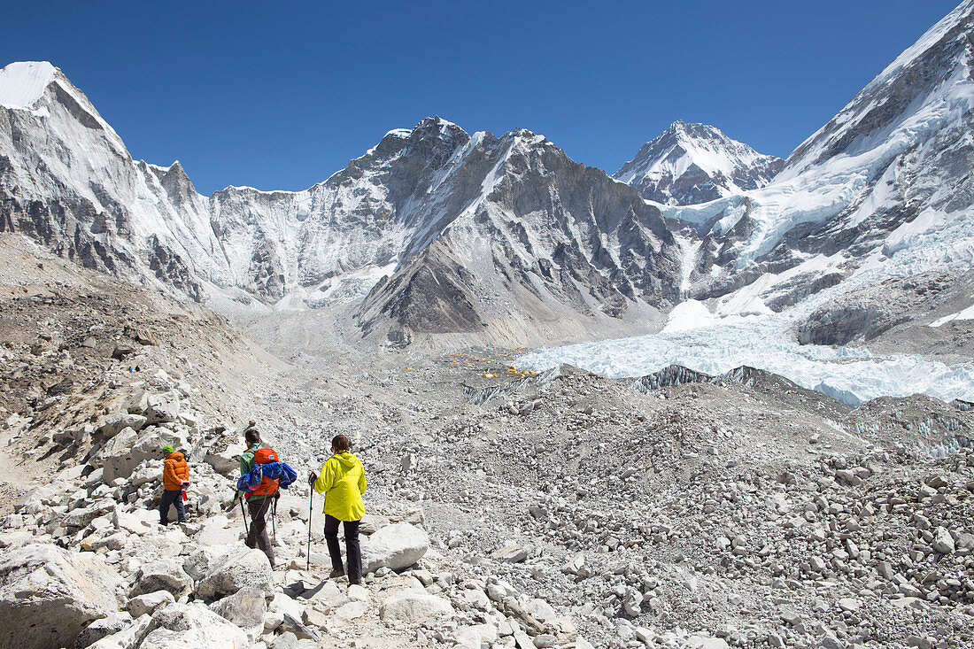 Drei Wanderer erreichen das Everest Base Camp nach einem Trekking durch das nepalesische Khumbu-Ta