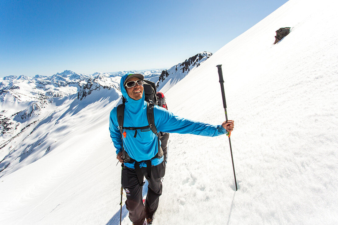 Male skier smiling while traversing deep snow in high mountains, Leavenworth, Washington, USA