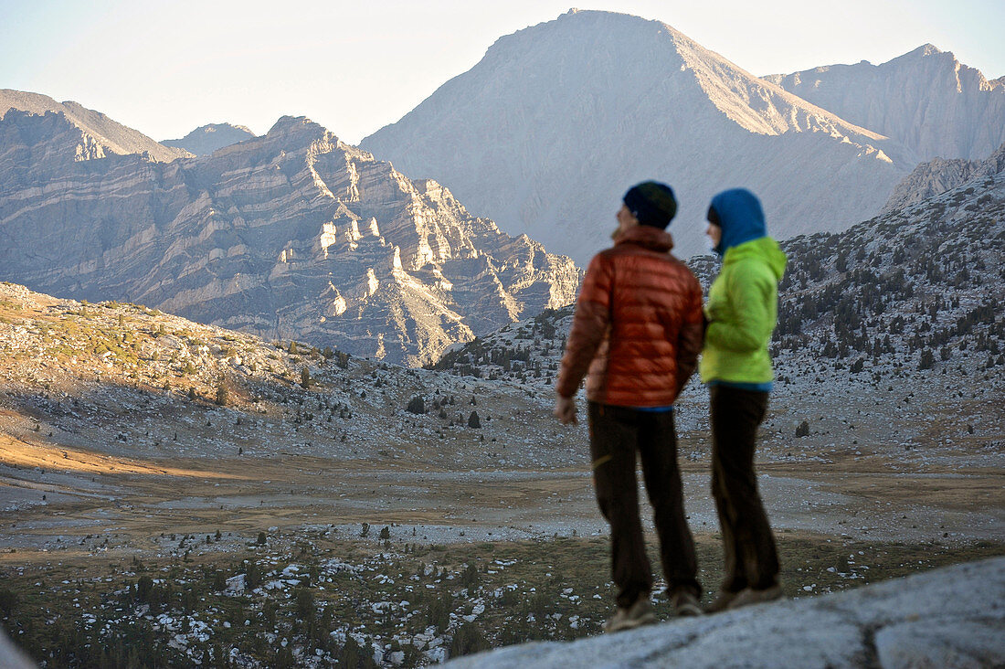 A couple watches sunrise over the mountains from the Puppet Lake Basin on a two-week trek of the Sierra High Route in the John Muir Wilderness in California. The 200-mile route roughly parallels the popular John Muir Trail through the Sierra Nevada Range of California from Kings Canyon National Park to Yosemite National Park. 