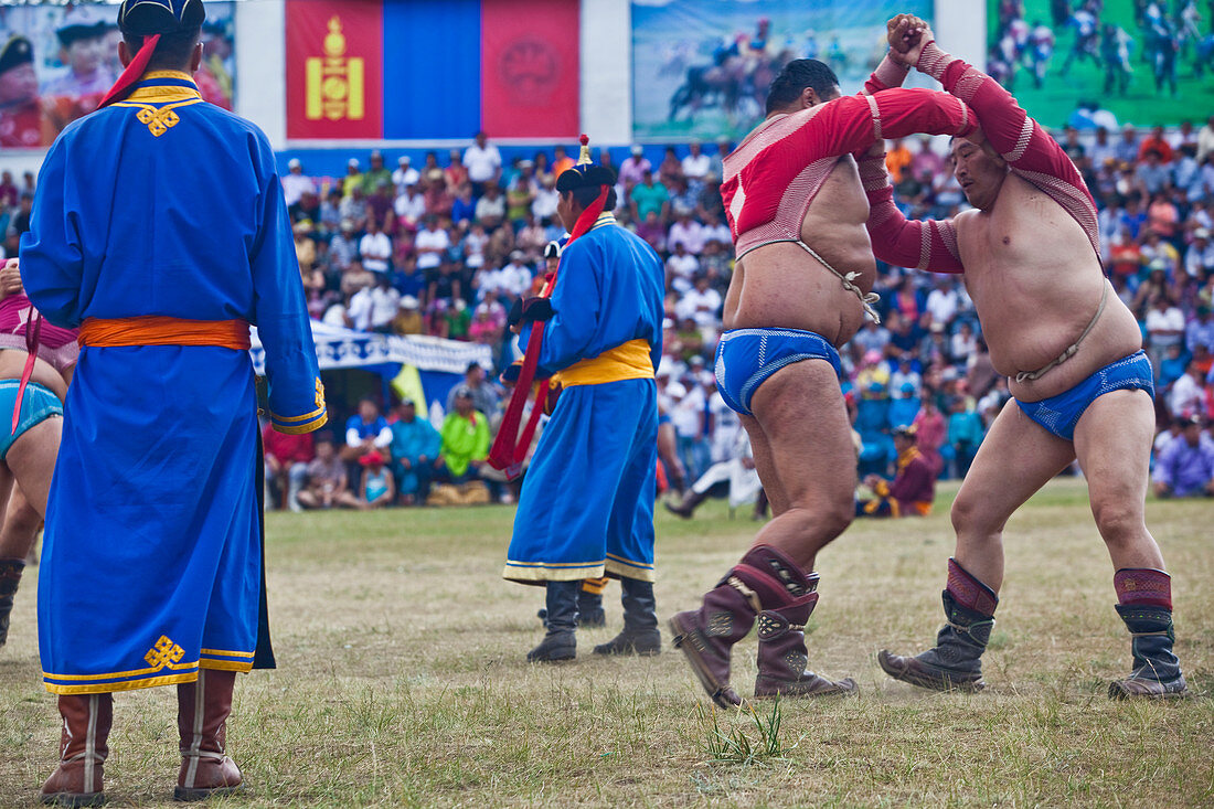 The wrestlers fight simultaneously in front of an excited audience. The round ends when one of the contestants touches the ground with their knee or elbow. Often wrestling becomes a match between ecto and endomorphs ? long, lanky, lean, sinewy, hairless muscled men with long arms who end up battling sumo-sized men with thighs the size of sequoia trees. Usually the big men win and become lions, elephants of their district. Annual Naadam Festival in Naadam Festival, Tsetserleg, Arkhangai Province, Mongolia