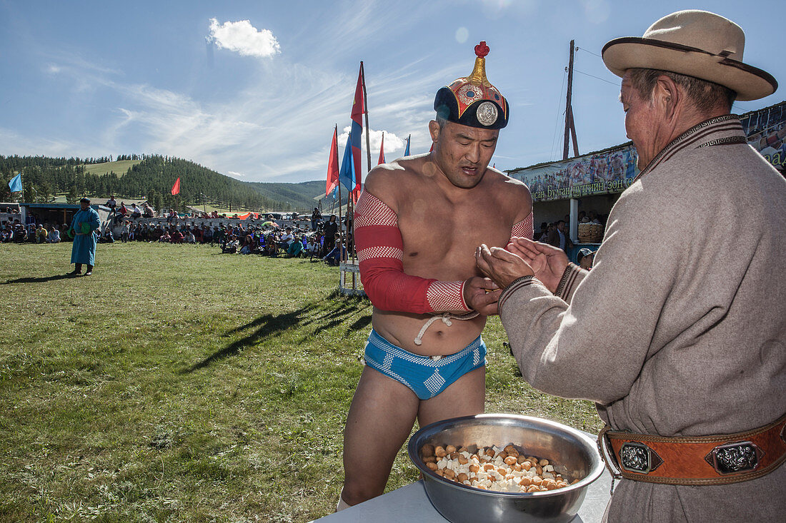 A Mongol wrestler, full of pride, grabbing a handful of the cheese which he will toss into the sky and out to the crowd of his admirers. Annual Naadam Festival in Tsetserleg, Arkhangai Province, Mongolia