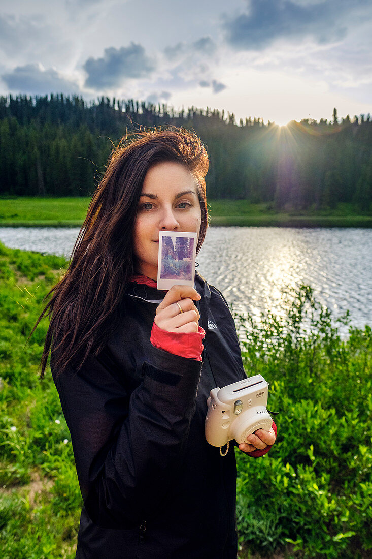 Woman holding instant camera and photograph on Colorado Trail, Colorado, USA