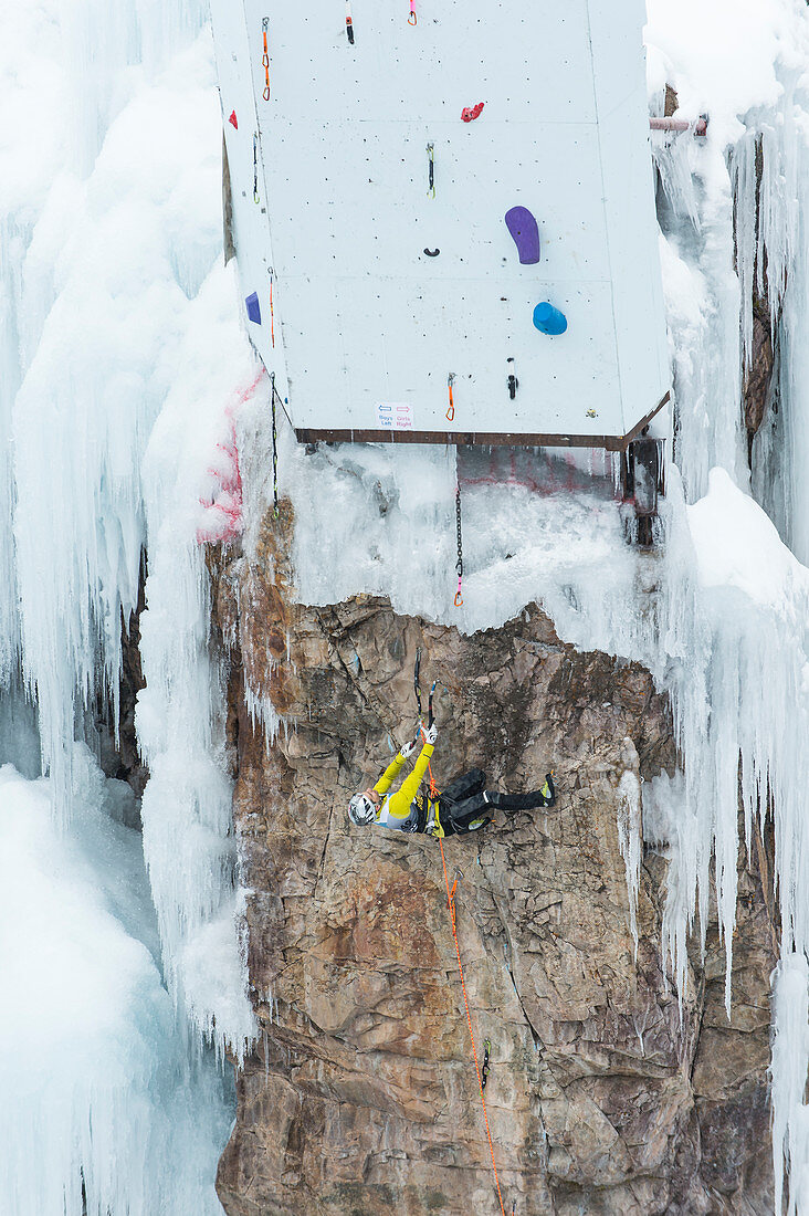 Male ice climber clinging horizontally to rocks on competition route, Ouray Ice Park, Colorado, USA