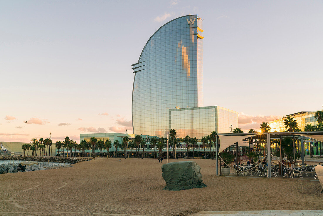 View of exterior of modern hotel skyscraper at sunset with palm trees, Barcelona, Catalonia, Spain