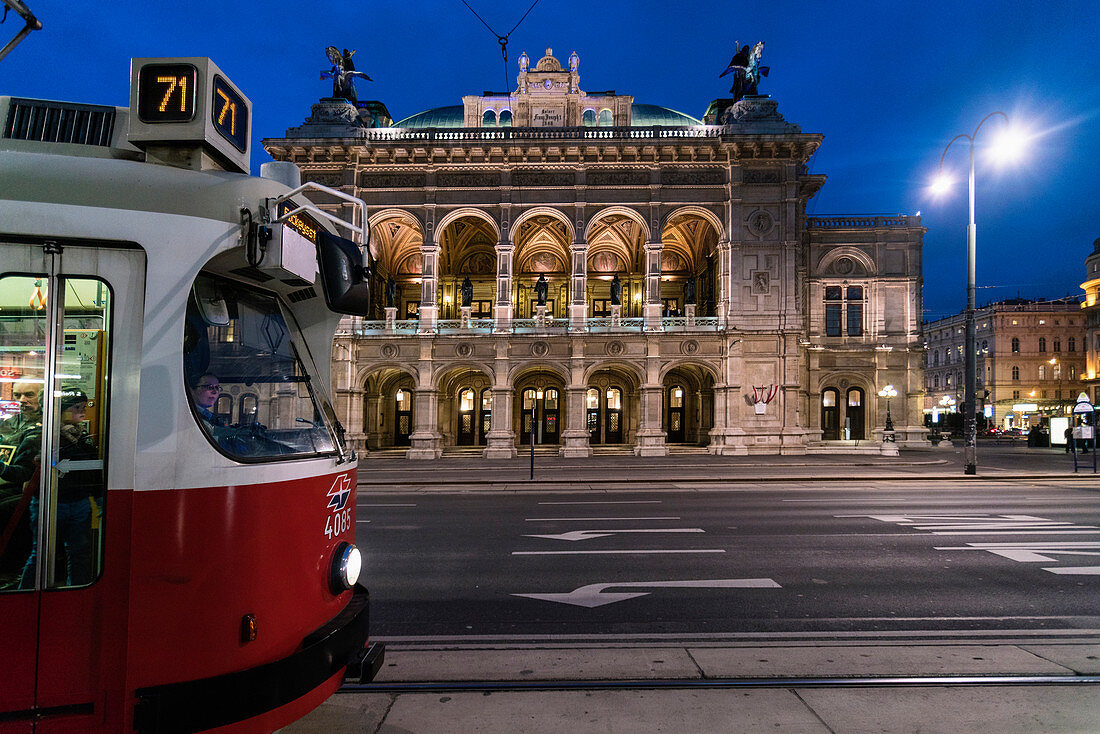 Beleuchtete Wiener Staatsoper nachts mit Straßenbahn im Vordergrund, Wien, Österreich