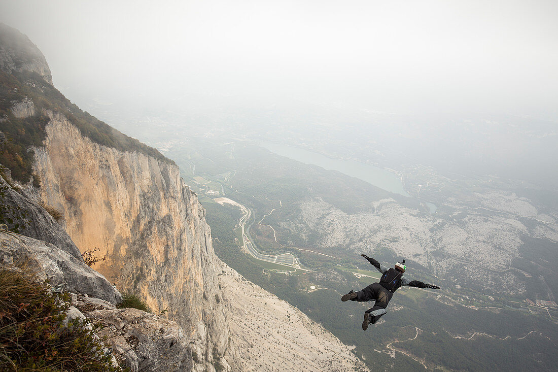 Base jumper mid air right after cliff jump during foggy weather, Brento, Venetien, Italy