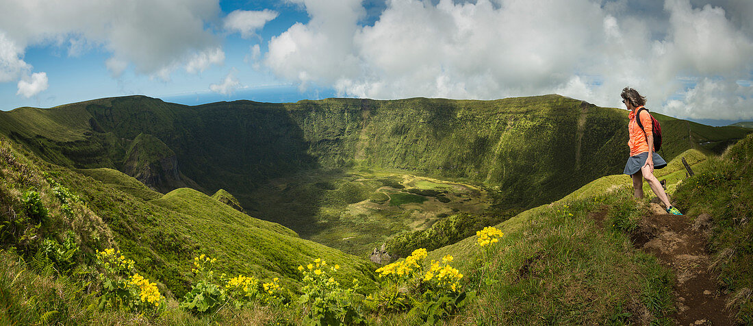 Hiker walking on hilltop dirt path over Cabeco Gordo crater, Faial, Portugal