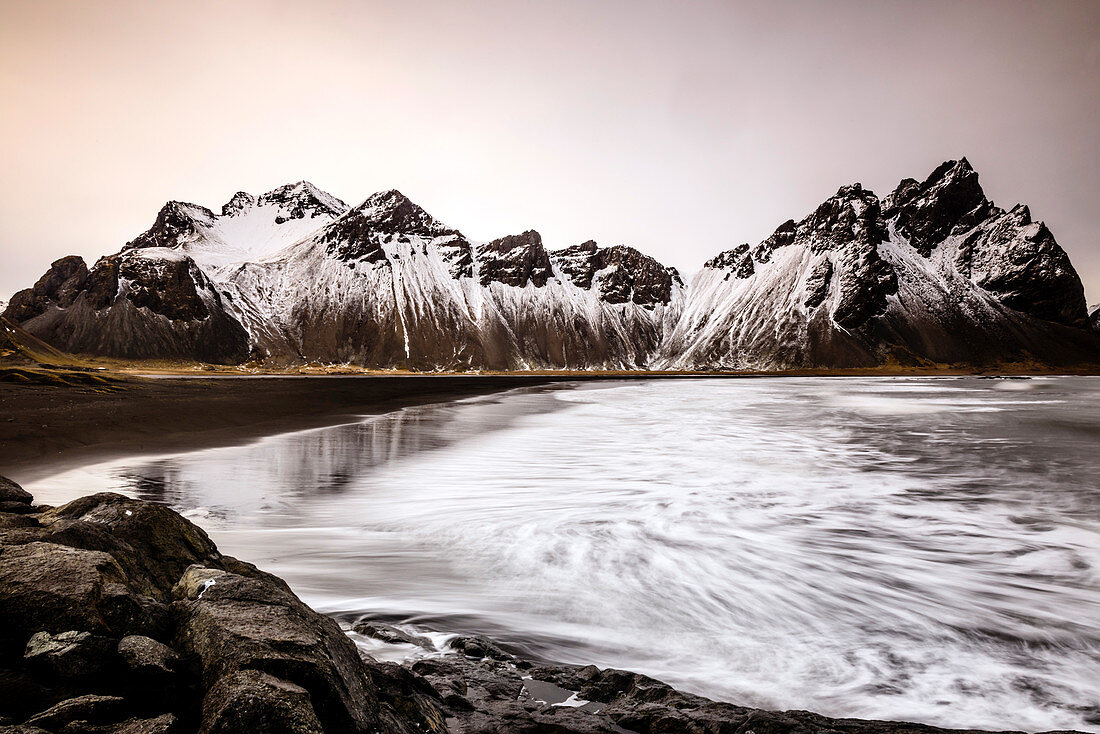 Ocean waves on beach under snowy mountains, Vestrahorn mountain, Iceland