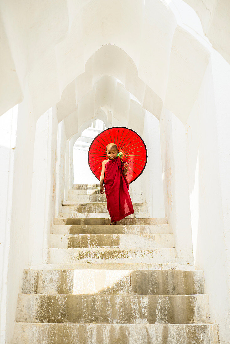 Asian Buddhist monk carrying umbrella on staircase at Hsinbyume Pagoda, Mandalay, Sagaing, Myanmar